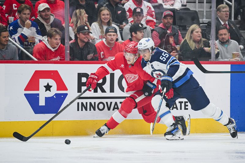 Oct 30, 2024; Detroit, Michigan, USA; Winnipeg Jets center Mark Scheifele (55) and Detroit Red Wings defenseman Simon Edvinsson (77) battle for the puck during the first period at Little Caesars Arena. Mandatory Credit: Tim Fuller-Imagn Images