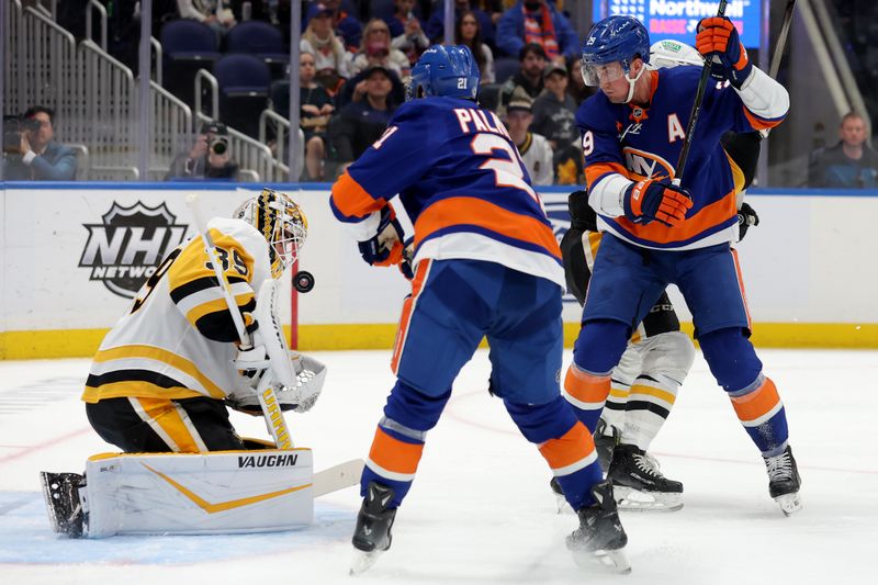 Nov 5, 2024; Elmont, New York, USA; Pittsburgh Penguins goaltender Alex Nedeljkovic (39) plays the puck against New York Islanders centers Kyle Palmieri (21) and center Brock Nelson (29) during the second period at UBS Arena. Mandatory Credit: Brad Penner-Imagn Images