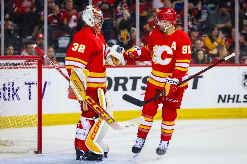 Apr 18, 2024; Calgary, Alberta, CAN; Calgary Flames goaltender Dustin Wolf (32) and center Nazem Kadri (91) celebrates win against San Jose Sharks at Scotiabank Saddledome. Mandatory Credit: Sergei Belski-USA TODAY Sports