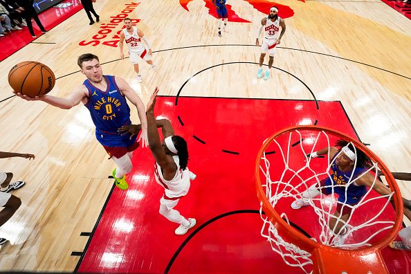 TORONTO, ON - DECEMBER 20: Christian Braun #0 of the Denver Nuggets goes to the basket against Precious Achiuwa #5 of the Toronto Raptors during the second half at Scotiabank Arena on December 20, 2023 in Toronto, Ontario, Canada. NOTE TO USER: User expressly acknowledges and agrees that, by downloading and/or using this Photograph, user is consenting to the terms and conditions of the Getty Images License Agreement. (Photo by Andrew Lahodynskyj/Getty Images)