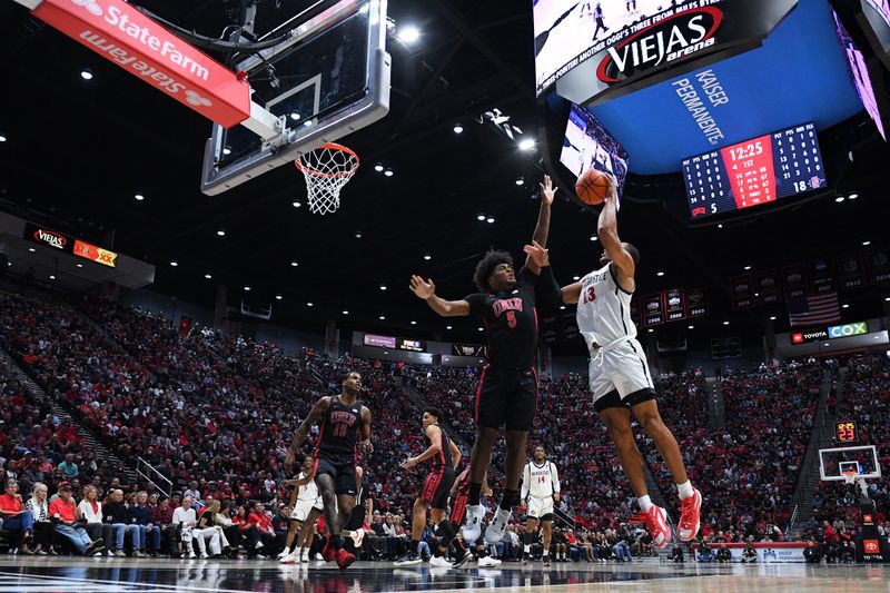 Jan 6, 2024; San Diego, California, USA; San Diego State Aztecs forward Jaedon LeDee (13) shoots the ball over UNLV Rebels forward Rob Whaley Jr. (5) during the first half at Viejas Arena. Mandatory Credit: Orlando Ramirez-USA TODAY Sports