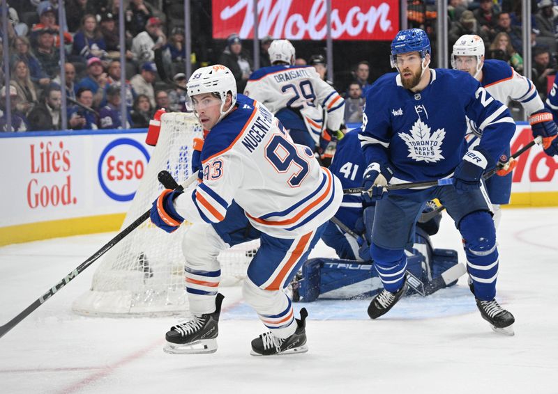 Nov 16, 2024; Toronto, Ontario, CAN;  Edmonton Oilers forward Ryan Nugent-Hopkins (93) pursues a loose puck ahead of Toronto Maple Leafs defenseman Jani Hakanpaa (28) in the second period at Scotiabank Arena. Mandatory Credit: Dan Hamilton-Imagn Images