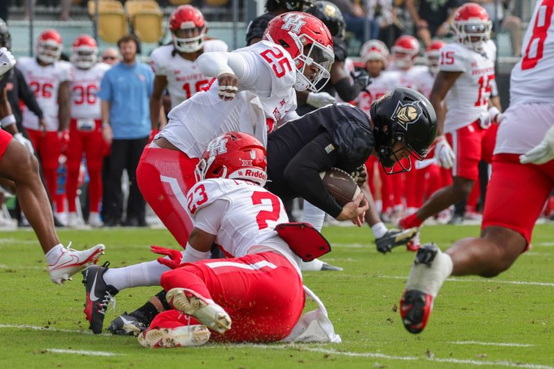 Nov 25, 2023; Orlando, Florida, USA; UCF Knights quarterback John Rhys Plumlee (10) is tackled by Houston Cougars defensive back Isaiah Hamilton (23) and linebacker Jamal Morris (25) during the first quarter at FBC Mortgage Stadium. Mandatory Credit: Mike Watters-USA TODAY Sports