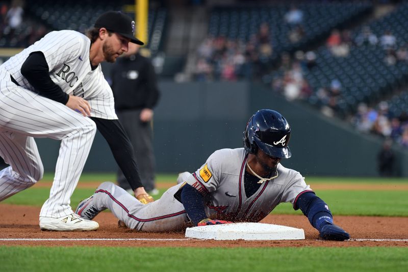 Apr 29, 2025; Denver, Colorado, USA; Atlanta Braves second base Ozzie Albies (1) slides into third base ahead of a tag by Colorado Rockies third base Ryan McMahon (24) during the fifth inning at Coors Field. Mandatory Credit: Christopher Hanewinckel-Imagn Images