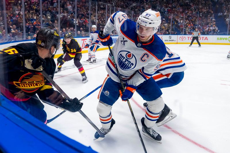 Nov 9, 2024; Vancouver, British Columbia, CAN; Edmonton Oilers forward Connor McDavid (97) battles with Vancouver Canucks defenseman Erik Brannstrom (26) during the second period at Rogers Arena. Mandatory Credit: Bob Frid-Imagn Images