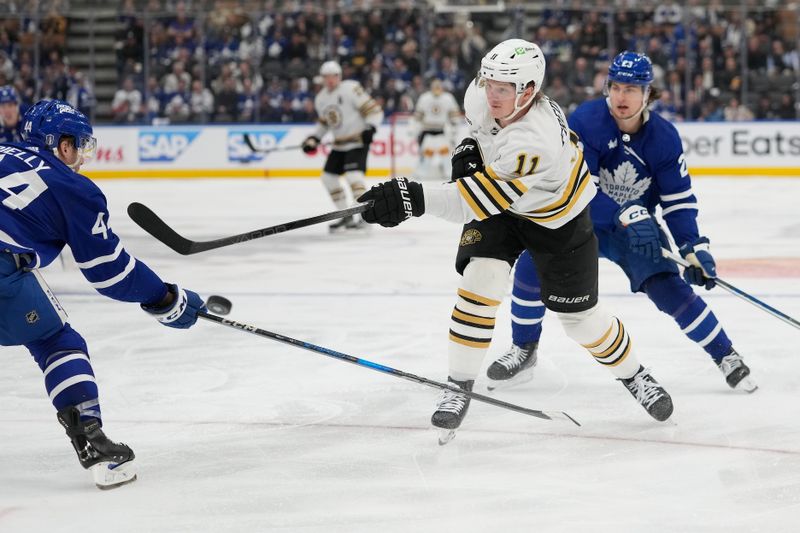 Apr 24, 2024; Toronto, Ontario, CAN; Boston Bruins forward Trent Frederic (11) shoots the puck as Toronto Maple Leafs defenseman Morgan Rielly (44) defends during the second period of game three of the first round of the 2024 Stanley Cup Playoffs at Scotiabank Arena. Mandatory Credit: John E. Sokolowski-USA TODAY Sports