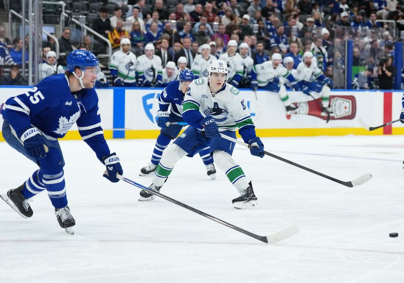 Jan 10, 2026; Toronto, Ontario, CAN; Vancouver Canucks left wing Liam Ohgren (92) battles for the puck with Toronto Maple Leafs defenseman Brandon Carlo (25) during the second period at Scotiabank Arena. Mandatory Credit: Nick Turchiaro-Imagn Images