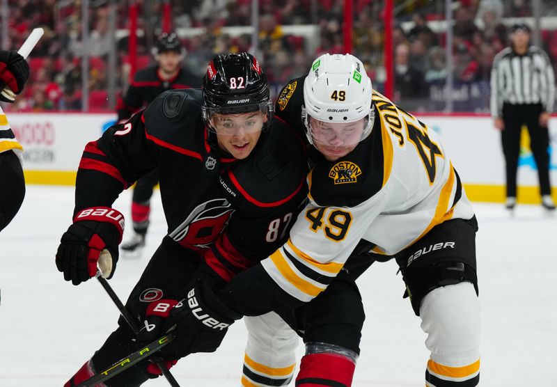 Oct 31, 2024; Raleigh, North Carolina, USA;  Carolina Hurricanes center Jesperi Kotkaniemi (82) and Boston Bruins left wing Max Jones (49) battle during the first period at Lenovo Center. Mandatory Credit: James Guillory-Imagn Images