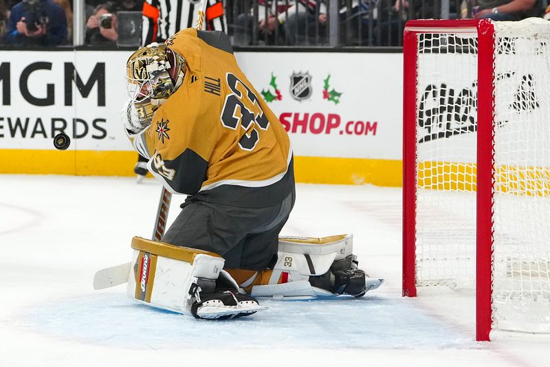 Nov 29, 2024; Las Vegas, Nevada, USA; Vegas Golden Knights goaltender Adin Hill (33) makes a save off his mask against the Winnipeg Jets during the first period at T-Mobile Arena. Mandatory Credit: Stephen R. Sylvanie-Imagn Images