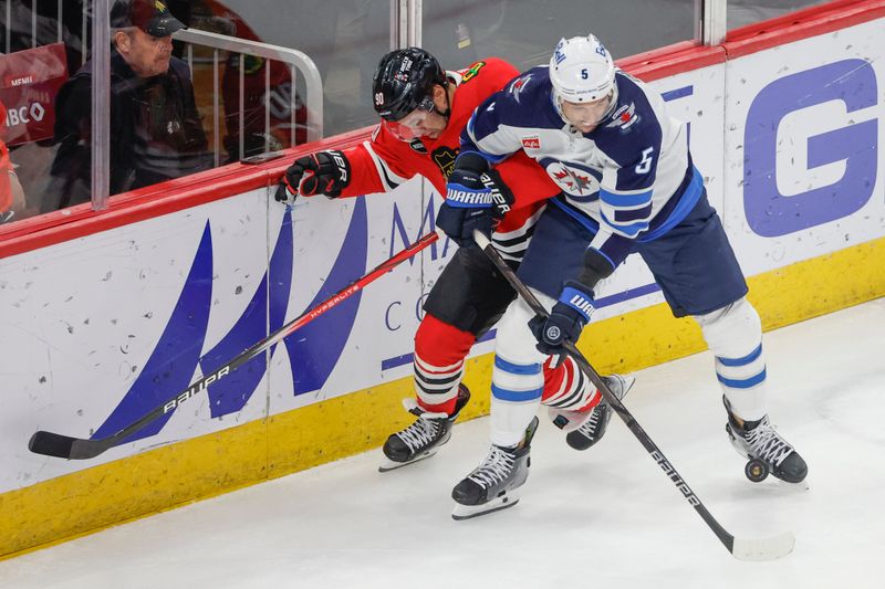 Feb 23, 2024; Chicago, Illinois, USA; Chicago Blackhawks center Tyler Johnson (90) battles for the puck with Winnipeg Jets defenseman Brenden Dillon (5) during the first period at United Center. Mandatory Credit: Kamil Krzaczynski-USA TODAY Sports