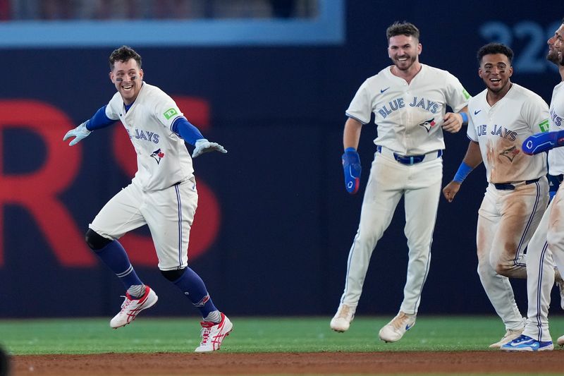 Jul 26, 2024; Toronto, Ontario, CAN; Toronto Blue Jays third baseman Ernie Clement (left) celebrates his walk off single towin the game against he Texas Rangers in the ninth inning at Rogers Centre. Mandatory Credit: John E. Sokolowski-USA TODAY Sports