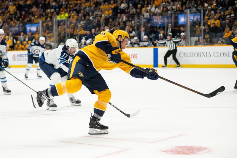 Nov 23, 2024; Nashville, Tennessee, USA;  Nashville Predators defenseman Alexandre Carrier (45) takes a shot against the Winnipeg Jets during the first period at Bridgestone Arena. Mandatory Credit: Steve Roberts-Imagn Images