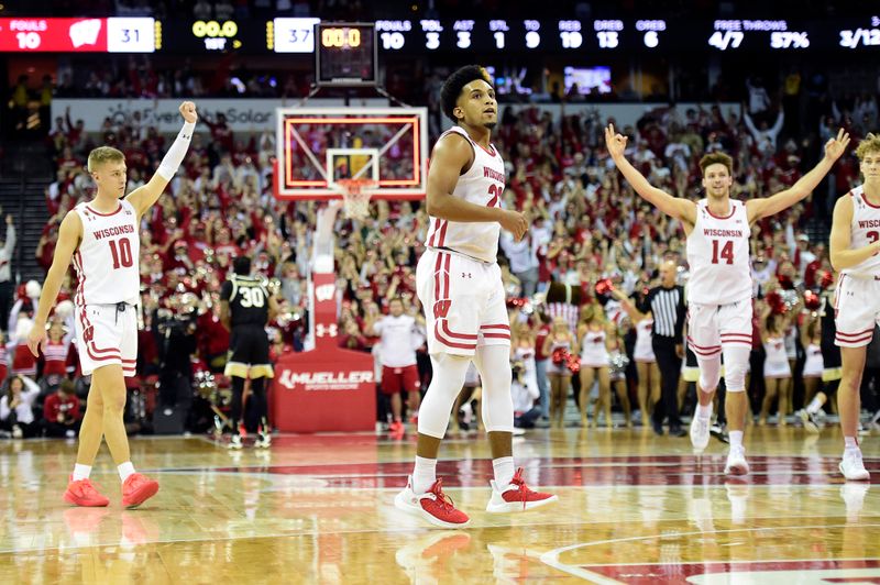 Nov 29, 2022; Madison, Wisconsin, USA;  Wisconsin Badgers guard Chucky Hepburn (23) looks on as teammates Isaac Lindsey (10) and Carter Gilmore (14) celebrate his buzzer-beating shot at the end of the first half at the Kohl Center. Mandatory Credit: Kayla Wolf-USA TODAY Sports