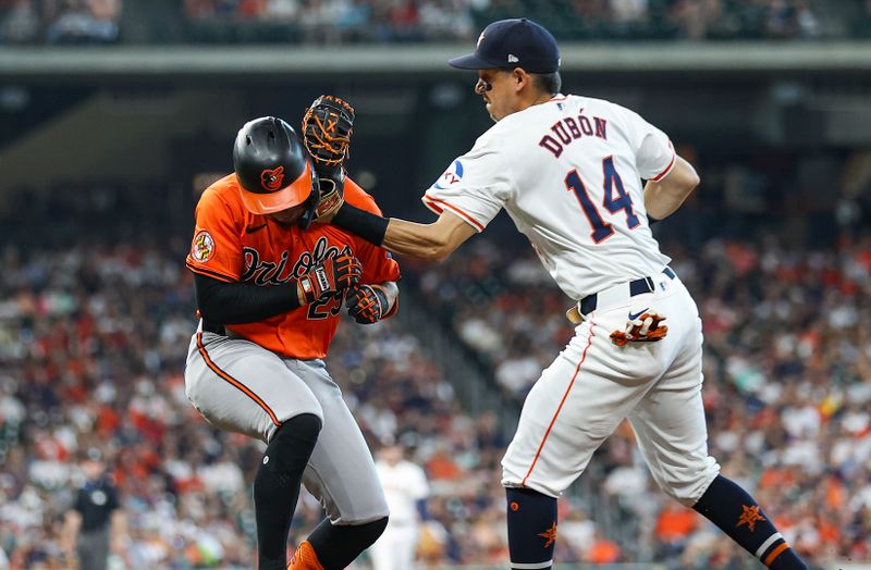 Jun 22, 2024; Houston, Texas, USA; Baltimore Orioles third baseman Ramon Urias (29) is tagged in the face by Houston Astros first baseman Mauricio Dubon (14) on a play during the third inning at Minute Maid Park. Mandatory Credit: Troy Taormina-USA TODAY Sports