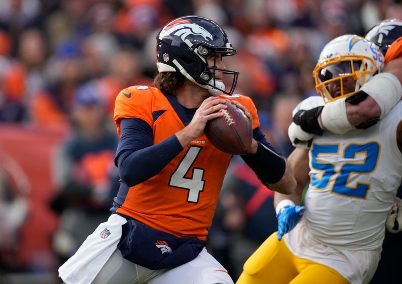 Denver Broncos quarterback Jarrett Stidham (4) avoids Los Angeles Chargers linebacker Khalil Mack (52) in the first half of an NFL football game in Empower Field at Mile High Sunday, Dec. 31, 2023, in Denver. (AP Photo/David Zalubowski)