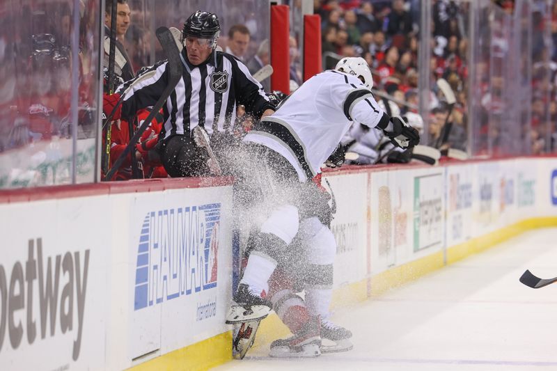 Feb 23, 2023; Newark, New Jersey, USA; Linesman Brad Kovachik (71) falls onto the New Jersey Devils bench after being hit by New Jersey Devils center Dawson Mercer (91) and Los Angeles Kings right wing Adrian Kempe (9) during the first period at Prudential Center. Mandatory Credit: Ed Mulholland-USA TODAY Sports