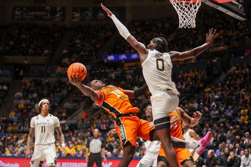 Jan 4, 2025; Morgantown, West Virginia, USA; Oklahoma State Cowboys guard Jamyron Keller (14) shoots in the lane against West Virginia Mountaineers center Eduardo Andre (0) during the second half at WVU Coliseum. Mandatory Credit: Ben Queen-Imagn Images
