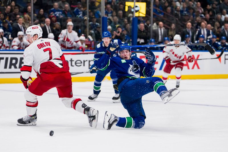 Dec 9, 2023; Vancouver, British Columbia, CAN; Vancouver Canucks forward Nils Hoglander (21) collides with Carolina Hurricanes defenseman Dmitry Orlov (7) in the third period at Rogers Arena. Vancouver won 4-3. Mandatory Credit: Bob Frid-USA TODAY Sports