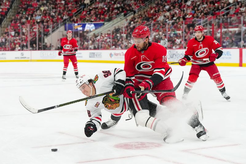 Jan 22, 2026; Raleigh, North Carolina, USA;  Carolina Hurricanes defenseman K'andre Miller (19) checks Chicago Blackhawks center Connor Bedard (98) during the second period at Lenovo Center. Mandatory Credit: James Guillory-Imagn Images