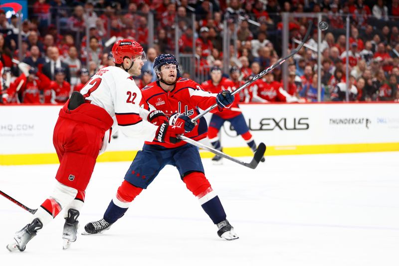 Mar 22, 2024; Washington, District of Columbia, USA; Washington Capitals center Connor McMichael (24) reaches for the puck in front of Carolina Hurricanes defenseman Brett Pesce (22) during the third period at Capital One Arena. Mandatory Credit: Amber Searls-USA TODAY Sports