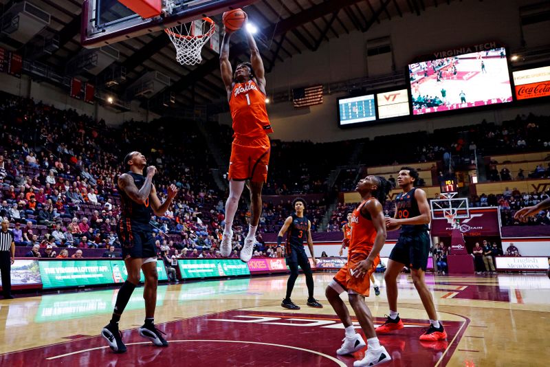 Jan 4, 2025; Blacksburg, Virginia, USA; Virginia Tech Hokies forward Tobi Lawal (1) dunks the ball against Miami Hurricanes guard Matthew Cleveland (0) during the first half at Cassell Coliseum. Mandatory Credit: Peter Casey-Imagn Images