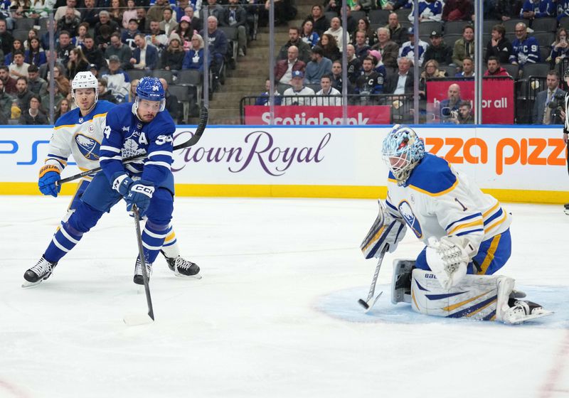 Mar 6, 2024; Toronto, Ontario, CAN; Toronto Maple Leafs center Auston Matthews (34) battles for the puck with Buffalo Sabres defenseman Jacob Bryson (78) in front of  goaltender Ukko-Pekka Luukkonen (1) during the first period at Scotiabank Arena. Mandatory Credit: Nick Turchiaro-USA TODAY Sports