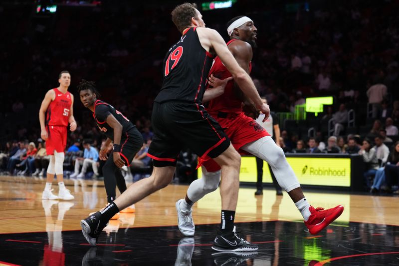 MIAMI, FLORIDA - DECEMBER 12: Bam Adebayo #13 of the Miami Heat drives to the basket against Jakob Poeltl #19 of the Toronto Raptors during the second quarter at Kaseya Center on December 12, 2024 in Miami, Florida. NOTE TO USER: User expressly acknowledges and agrees that, by downloading and or using this Photograph, user is consenting to the terms and conditions of the Getty Images License Agreement. (Photo by Rich Storry/Getty Images)