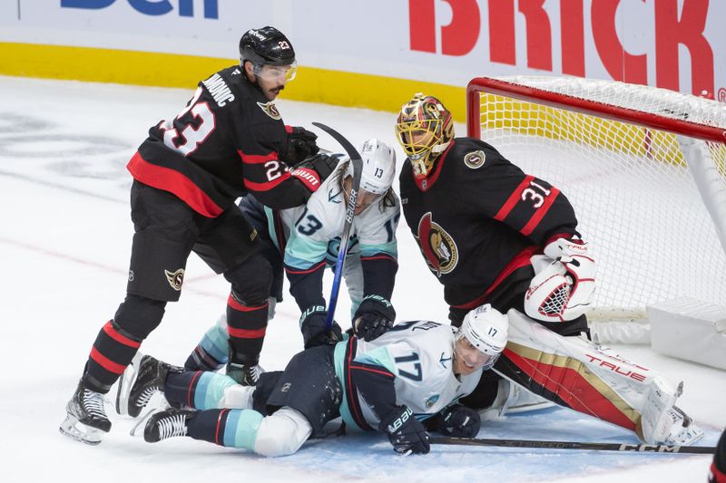 Nov 2, 2024; Ottawa, Ontario, CAN; Seattle Kraken left wing Brandon Tanev (13) and Jaden Schwartz (17) are taken down by Ottawa Senators defenseman Travis Hamonic (23) as they stand in front of goalie Anton Forsberg (31) in the third period at the Canadian Tire Centre. Mandatory Credit: Marc DesRosiers-Imagn Images