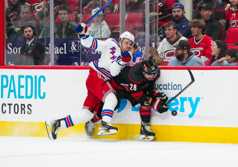 Nov 27, 2024; Raleigh, North Carolina, USA;  New York Rangers defenseman Ryan Lindgren (55) checks Carolina Hurricanes left wing William Carrier (28) during the third period at Lenovo Center. Mandatory Credit: James Guillory-Imagn Images