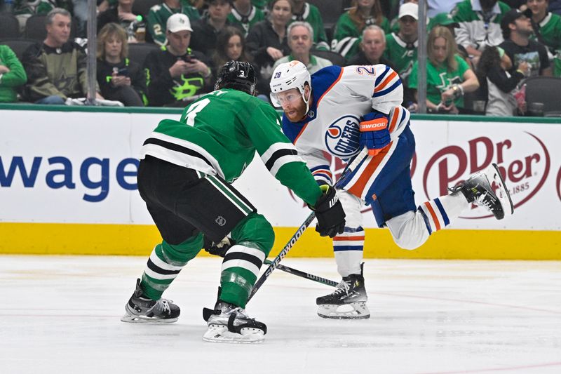 May 25, 2024; Dallas, Texas, USA; Edmonton Oilers right wing Connor Brown (28) shoots the puck past Dallas Stars defenseman Miro Heiskanen (4) during the third period in game two of the Western Conference Final of the 2024 Stanley Cup Playoffs at American Airlines Center. Mandatory Credit: Jerome Miron-USA TODAY Sports