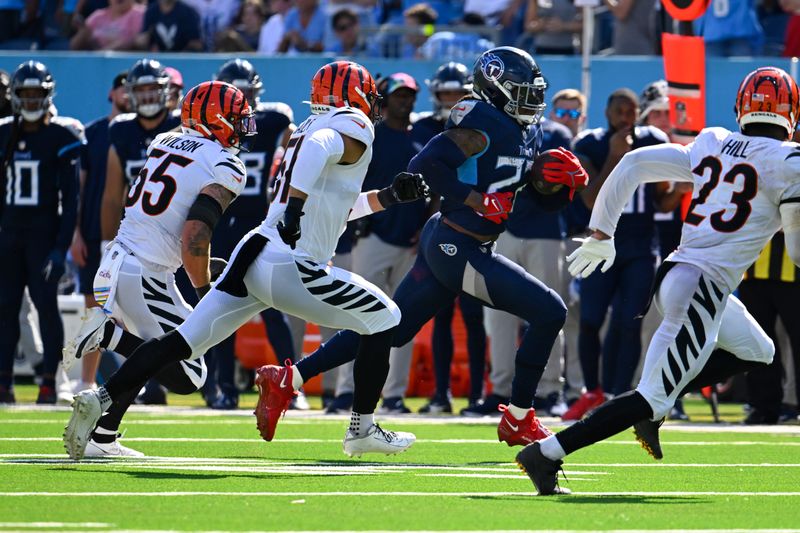 Tennessee Titans running back Derrick Henry (22) runs runs as Cincinnati Bengals linebacker Logan Wilson (55), safety Dax Hill (23) and linebacker Markus Bailey defend during an NFL football game Sunday, Sept. 30, 2023 in Nashville, Tenn. (AP Photo/John Amis)