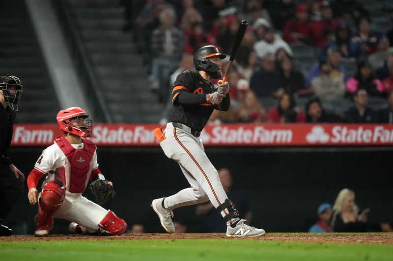 Apr 22, 2024; Anaheim, California, USA; Baltimore Orioles left fielder Colton Cowser (17) hits a solo home run in the seventh inning as Los Angeles Angels catcher Logan O'Hoppe (14) watches at Angel Stadium. Mandatory Credit: Kirby Lee-USA TODAY Sports