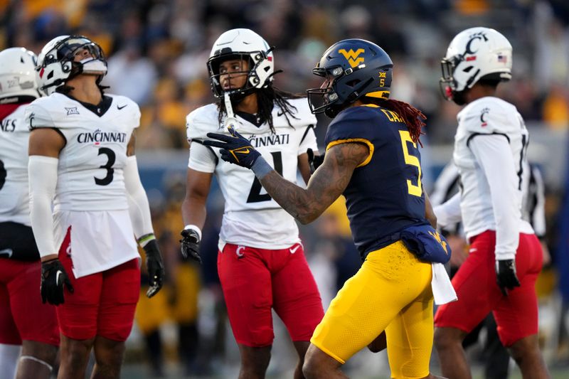 Nov 18, 2023; Morgantown, West Virginia, USA; West Virginia Mountaineers wide receiver Devin Carter (5) signals for a first down after a catch as Cincinnati Bearcats safety Deshawn Pace (3) reacts in the third quarter at Milan Puskar Stadium. West Virginia won 42-21. Mandatory Credit: Kareem Elgazzar-USA TODAY Sports