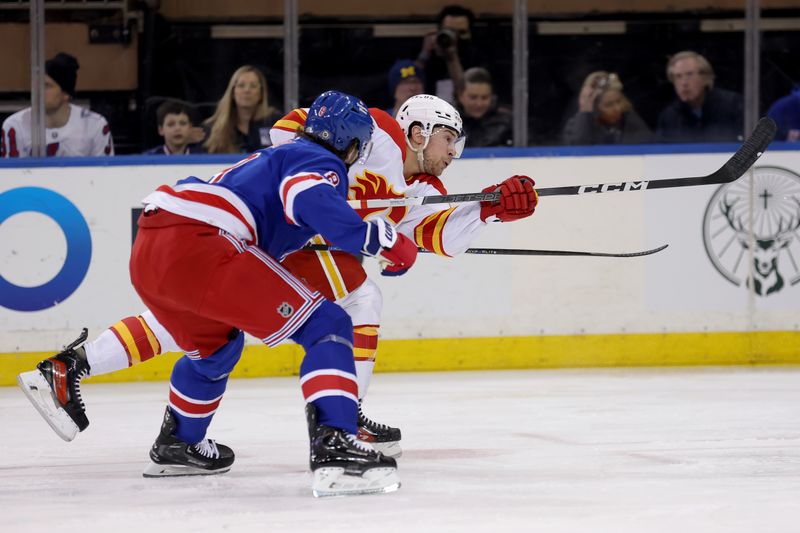 Feb 12, 2024; New York, New York, USA; Calgary Flames left wing Andrew Mangiapane (88) follows through on a shot against New York Rangers defenseman Jacob Trouba (8) during the second period at Madison Square Garden. Mandatory Credit: Brad Penner-USA TODAY Sports