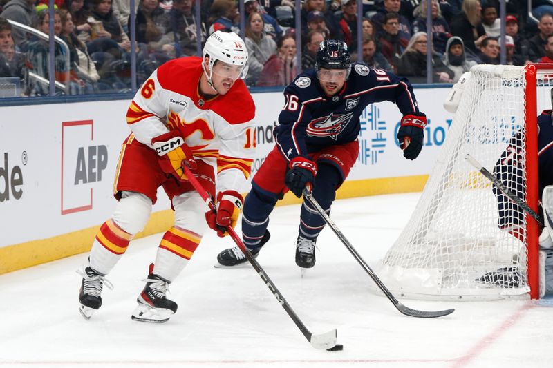 Jan 13, 2026; Columbus, Ohio, USA; Calgary Flames center Morgan Frost (16) carries the puck as Columbus Blue Jackets center Brendan Gaunce (16) trails the play during the first period at Nationwide Arena. Mandatory Credit: Russell LaBounty-Imagn Images