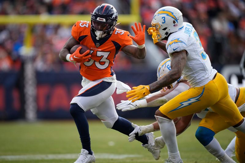 Denver Broncos running back Javonte Williams (33) and Los Angeles Chargers safety Derwin James Jr. (3) in the first half of an NFL football game in Empower Field at Mile High Sunday, Dec. 31, 2023, in Denver. (AP Photo/David Zalubowski)