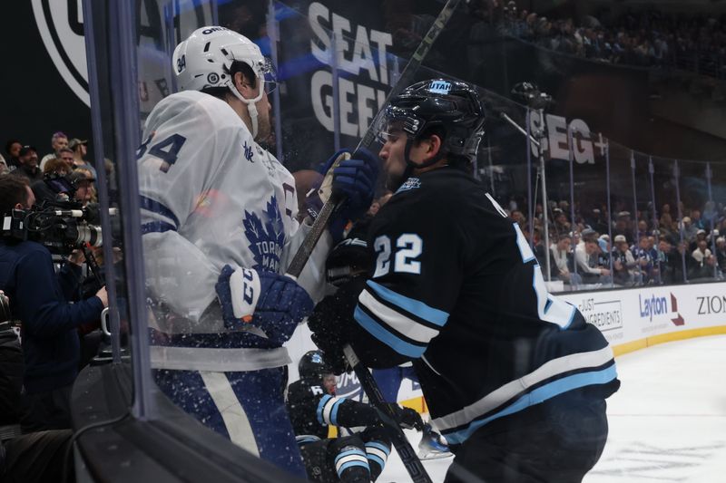 Mar 10, 2025; Salt Lake City, Utah, USA; Toronto Maple Leafs defenseman Morgan Rielly (44) and Utah Hockey Club center Jack McBain (22) go to the boards during the second period at Delta Center. Mandatory Credit: Rob Gray-Imagn Images