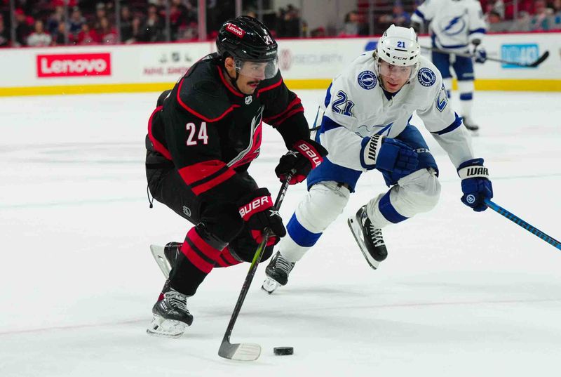 Nov 24, 2023; Raleigh, North Carolina, USA; Carolina Hurricanes center Seth Jarvis (24) skates with the puck against Tampa Bay Lightning center Brayden Point (21) during the third period at PNC Arena. Mandatory Credit: James Guillory-USA TODAY Sports