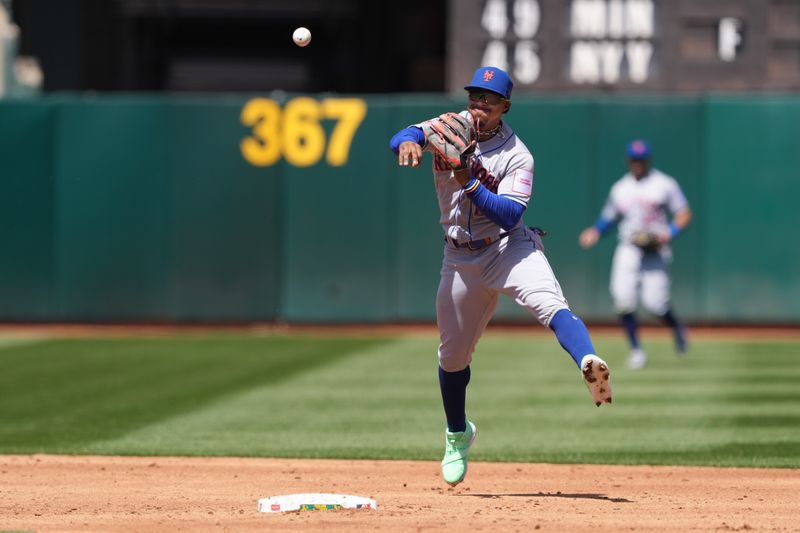 Apr 16, 2023; Oakland, California, USA; New York Mets shortstop Francisco Lindor (12) throws the ball to first base to record an out against the Oakland Athletics during the third inning at RingCentral Coliseum. Mandatory Credit: Darren Yamashita-USA TODAY Sports