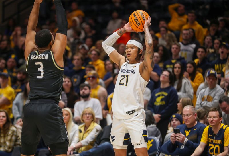 Feb 20, 2024; Morgantown, West Virginia, USA; West Virginia Mountaineers guard RaeQuan Battle (21) looks to pass the ball while defended by UCF Knights guard Darius Johnson (3) during the second half at WVU Coliseum. Mandatory Credit: Ben Queen-USA TODAY Sports