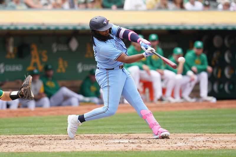 Jun 8, 2024; Oakland, California, USA; Toronto Blue Jays first baseman Vladimir Guerrero Jr. (27) hits a double against the Oakland Athletics in the fifth inning at Oakland-Alameda County Coliseum. Mandatory Credit: Cary Edmondson-USA TODAY Sports