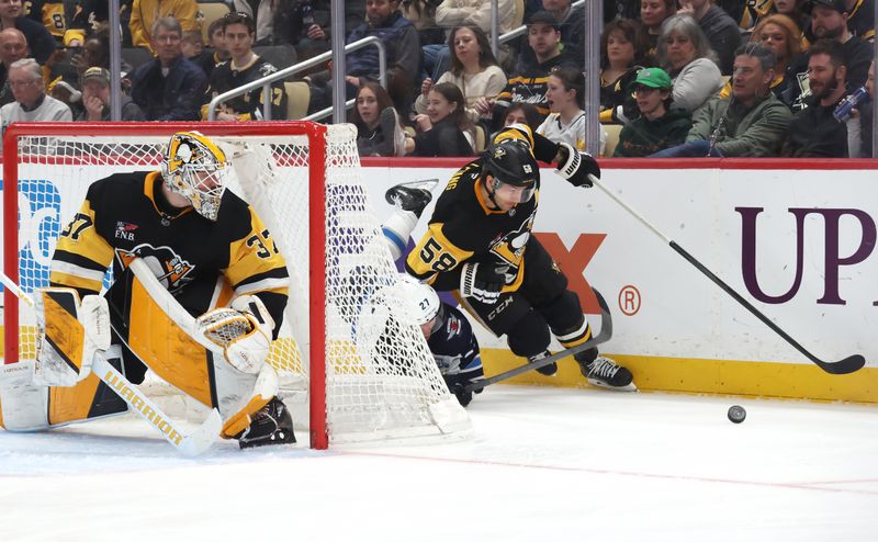 Mar 21, 2026; Pittsburgh, Pennsylvania, USA;  Pittsburgh Penguins defenseman Kris Letang (58) moves the puck behind his net against Winnipeg Jets right wing Isak Rosen (27) during the second period at PPG Paints Arena. Mandatory Credit: Charles LeClaire-Imagn Images