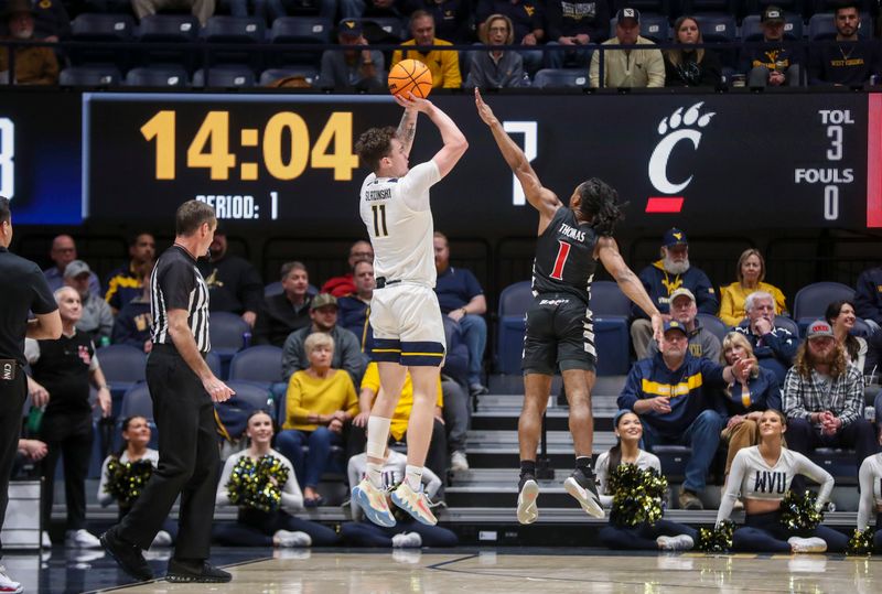 Jan 31, 2024; Morgantown, West Virginia, USA; West Virginia Mountaineers forward Quinn Slazinski (11) shoots a three pointer over Cincinnati Bearcats forward Kalu Ezikpe (1) during the first half at WVU Coliseum. Mandatory Credit: Ben Queen-USA TODAY Sports