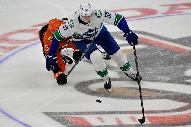 Nov 5, 2024; Anaheim, California, USA; Anaheim Ducks defenseman Urho Vaakanainen (5) reaches under Vancouver Canucks defenseman Tyler Myers (57) for the puck in the third period at Honda Center. Mandatory Credit: Jayne Kamin-Oncea-Imagn Images