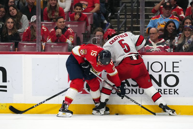 Nov 10, 2023; Sunrise, Florida, USA; Florida Panthers center Anton Lundell (15) and Carolina Hurricanes defenseman Jalen Chatfield (5) battle for the puck against the boards during the second period at Amerant Bank Arena. Mandatory Credit: Jasen Vinlove-USA TODAY Sports