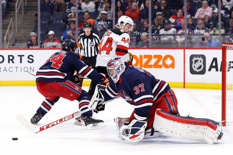 Apr 2, 2023; Winnipeg, Manitoba, CAN; Winnipeg Jets goaltender Connor Hellebuyck (37) makes a poke check on New Jersey Devils left wing Miles Wood (44) in the first period at Canada Life Centre. Mandatory Credit: James Carey Lauder-USA TODAY Sports