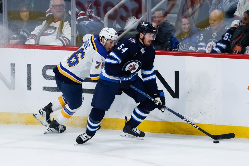 Feb 27, 2024; Winnipeg, Manitoba, CAN; Winnipeg Jets defenseman Dylan Samberg (54) skates away from St. Louis Blues forward Zack Bolduc (76) during the third period at Canada Life Centre. Mandatory Credit: Terrence Lee-USA TODAY Sports