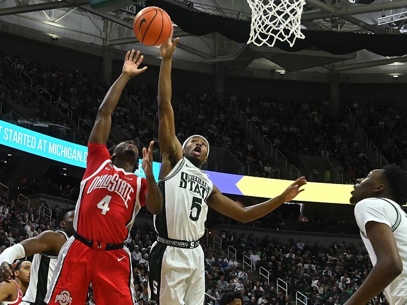 Feb 25, 2024; East Lansing, Michigan, USA;  Michigan State Spartans guard Tre Holloman (5) blocks a shot by Ohio State Buckeyes guard Dale Bonner (4) during the first half at Jack Breslin Student Events Center. Mandatory Credit: Dale Young-USA TODAY Sports