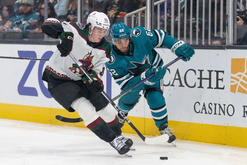 Dec 21, 2023; San Jose, California, USA; Arizona Coyotes center Logan Cooley (92) and San Jose Sharks right wing Kevin Labanc (62) fight for control of the puck during the second period at SAP Center at San Jose. Mandatory Credit: Stan Szeto-USA TODAY Sports