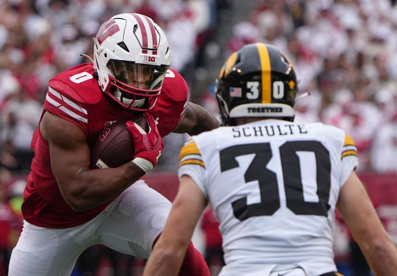 Oct 14, 2023; Madison, Wisconsin, USA; Wisconsin Badgers running back Braelon Allen (0) runs the ball against Iowa Hawkeyes defensive back Quinn Schulte (30) during the first quarter at Camp Randall Stadium. Mandatory Credit: Mark Hoffman-USA TODAY Sports